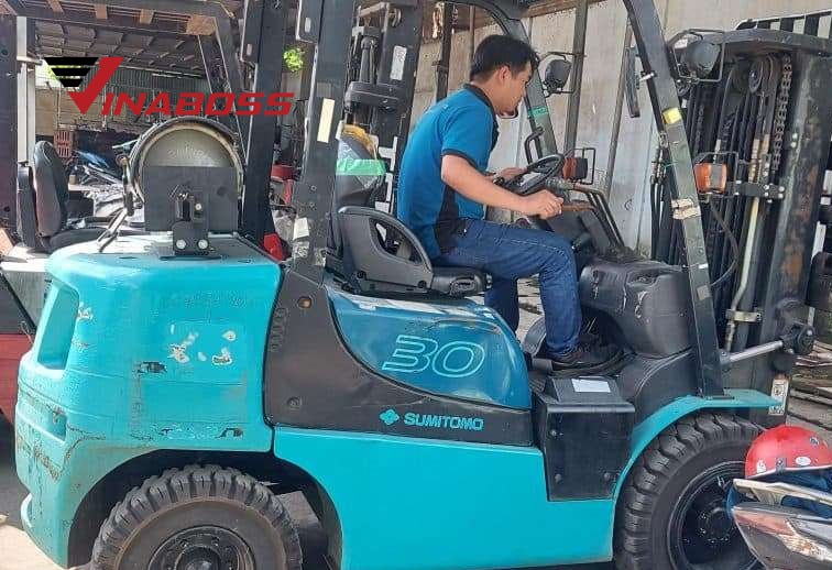 Một kỹ thuật viên chuyên nghiệp của Vinaboss đang sử dụng máy chẩn đoán lỗi hiện đại trên một chiếc xe nâng, thể hiện sự chuyên môn và công nghệ cao